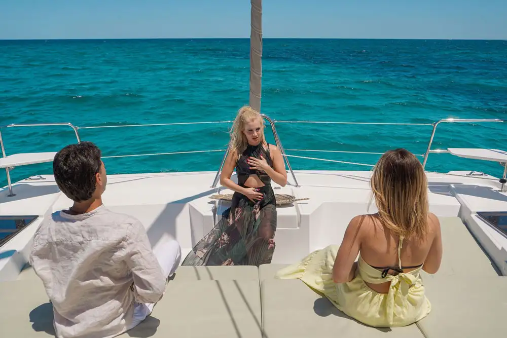 On a motor yacht, Linda guides a man and a woman to breathe deeply and correctly.